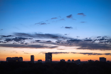 Fototapeta premium Light clouds in evening sky against the background of high-rise 