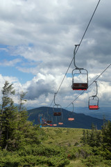 Lift in mountains summer against the background of green firs an