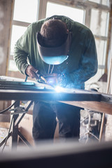 Industrial welder working a welding metal with protective mask