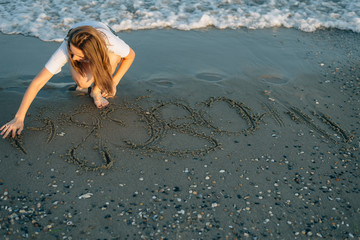 The girl writes on sand