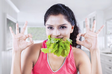 Woman with spinach and OK sign at home