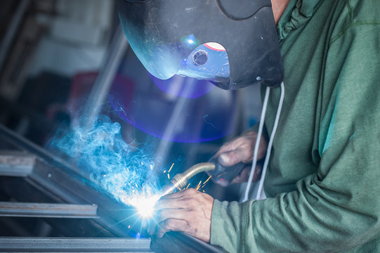 Industrial welder working a welding metal with protective mask