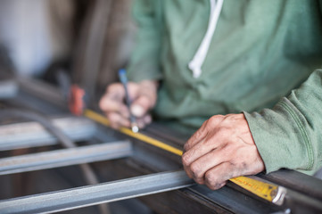 Worker measuring steel with measuring tape