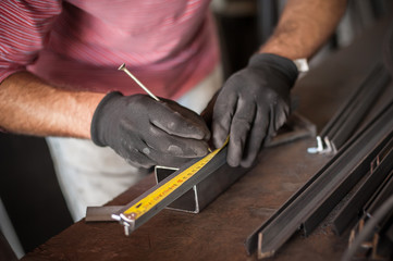 Worker measuring steel with measuring tape