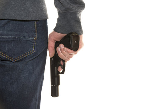 Armed person holding handgun wearing dark blue jeans and hoodie isolated on white background, copy space, close-up on gun