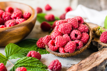 Raspberry in a bowl and in a plate, berries and leaves on a shabby  wood