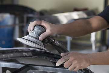 Auto body repair series: Closeup of mechanic sanding car bumper