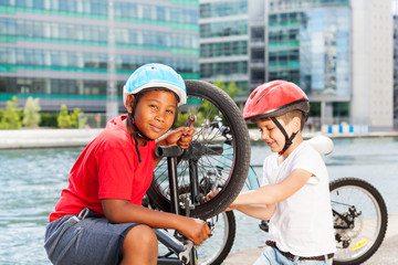 Children mechanics repairing bicycle outdoors