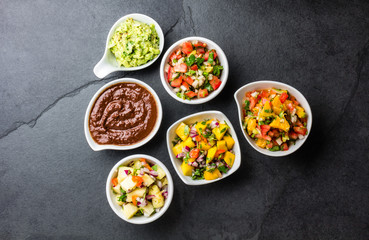 Traditional famous mexican sauces chocolate chili mole poblano, pico de gallo, avocado guacamole, salsa bandera, pinapple salsa, mango salsa on slate gray background
