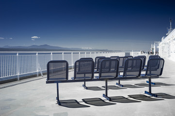 Seating and Western view of clear blue sky and the Strait of Georgia from the top deck of a passenger and vehicle ferry enroute from Tsawwassen to Victoria, BC, Canada.