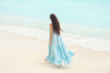 Fototapeta na wymiar Beautiful young woman on sea beach at resort