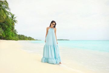 Fototapeta na wymiar Beautiful young woman on sea beach at tropical resort