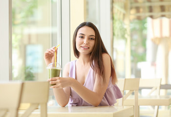 Romantic young lady enjoying tasty smoothie in cafe