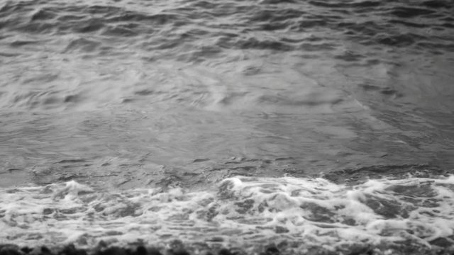 Sea waves crash on the pebbly shore and the water surface. Close-up