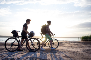 Two tourists with bicycle walking in the desert during the sunset in lake 