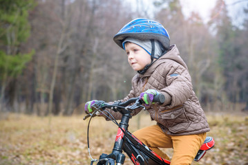 Fototapeta na wymiar child on a bicycle in the forest in early morning. Boy cycling outdoors in helmet