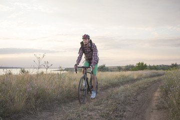 young man ride on the country road in the summer fields 