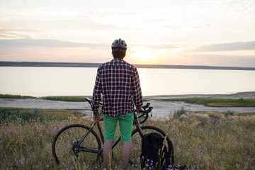 photo of bicycle rider outdoor in fields during the summer sunset in lake  