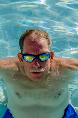 Mature man in a swimming pool, looking up - vertical photo
