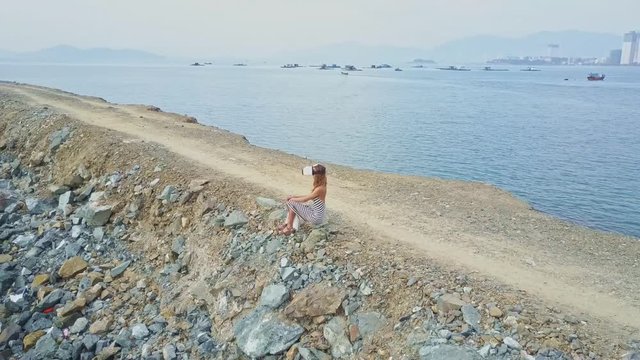 Drone Shows Girl in Helmet Sitting against Sailing Boats