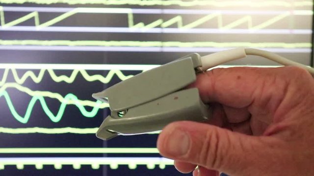 Finger  with measuring  device .Black monitor screen with line.