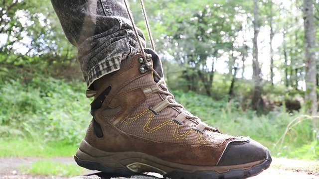 A man ties up shoelaces on boots for hikes in the mountains.