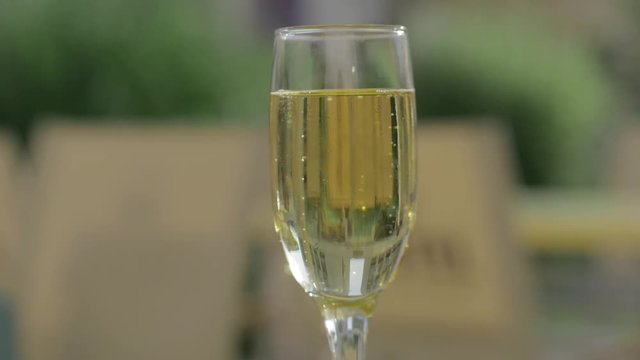 Hand raising a glass of champagne. Bubbles close-up. 4k.
