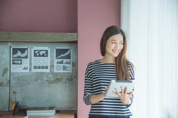 Beautiful asian woman smiling while using tablet computer