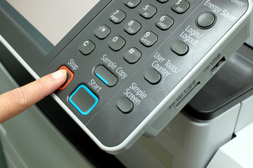 Finger pressing stop button on photocopy