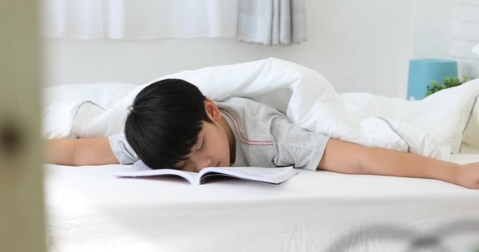 Asian cute boy reading a book before final test at home . be a sleep after read .
