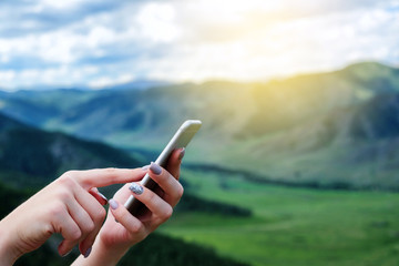 Woman's hands using mobile phone on the nature.