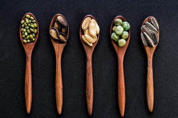 collection of grains in wooden spoon on black background.