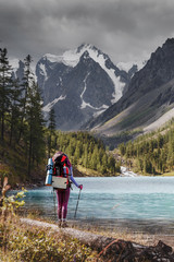 Adventure backpacking woman enjoying view of majestic blue mountain lake in Altai