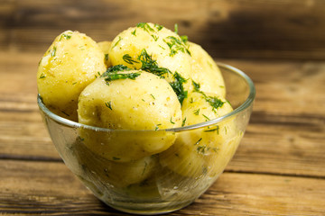 Boiled new potatoes with butter and dill on wooden table