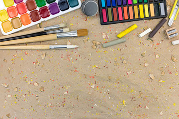 watercolor palette with paintbrushes different size and colorful pastels. colorful drawing supplies on desk.