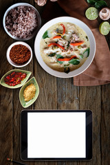 Blank screen tablet and Green Chicken Curry over wooden table.Thai cuisine