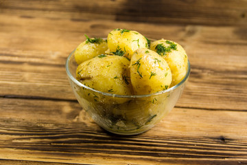 Boiled new potatoes with butter and dill on wooden table