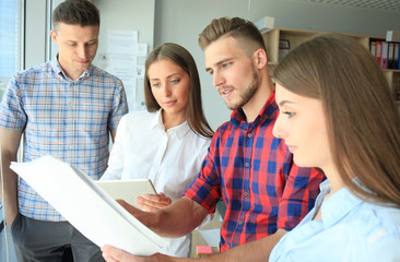Obraz premium Group of young modern people in smart casual wear having a brainstorm meeting while standing in the creative office.