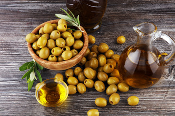 Bottle virgin olive oil and oil in a bowl with some olives