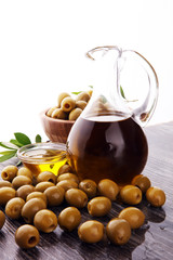 Bottle virgin olive oil and oil in a bowl with some olives