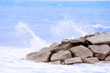 Sea wave to the beach with stone wall.