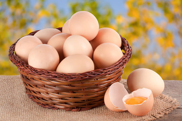 eggs in a wicker basket on a wooden board with blurred garden background