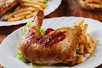 Roasted chicken legs with french fries and lettuce