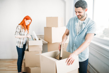 Young man unpacking cardboard boxes, housewarming