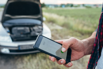 Male person hand with phone, broken car