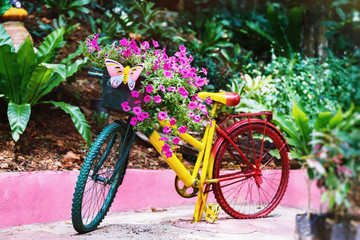 Fototapeta na wymiar Colorful painted bicycle decorated with flowers and butterfly outdoors at green tropical garden background.