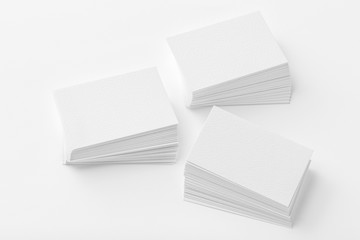 Mockup of three business cards stacks at white textured background.