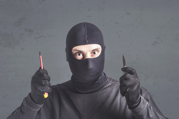 Masked thief holding a knife and a screwdriver. Threatening situation concept