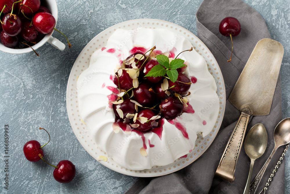 Wall mural homemade meringue cake pavlova with whipped cream, fresh cherry and sauce on light concrete texture 