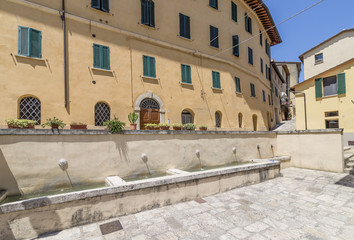 Fototapeta na wymiar Small fountains and tubs in Piazza Garibaldi square, historic center of Cetona, Siena, Italy, on a sunny day